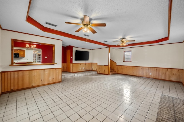 empty room with a tray ceiling, a wainscoted wall, visible vents, a textured ceiling, and stairs