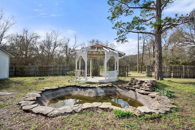 view of yard with a gazebo, fence, and a garden pond