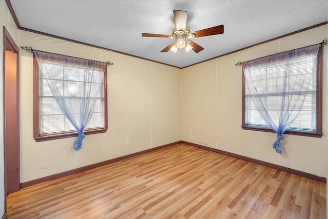 spare room featuring baseboards, crown molding, a textured ceiling, and light wood finished floors