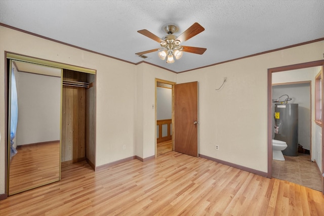 unfurnished bedroom featuring crown molding, a closet, wood finished floors, and electric water heater