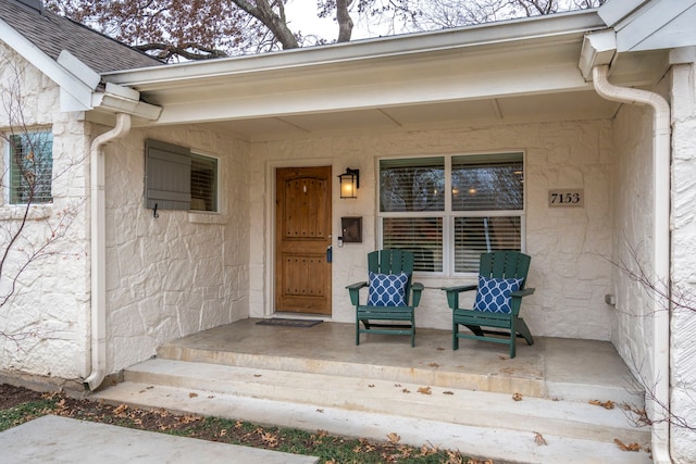 doorway to property with stone siding and roof with shingles