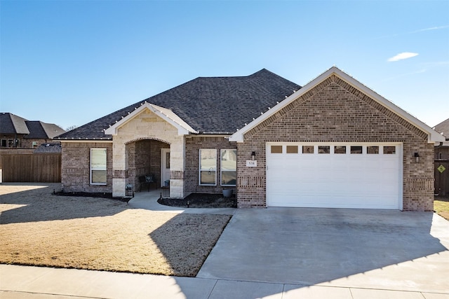 single story home with a shingled roof, concrete driveway, brick siding, and an attached garage