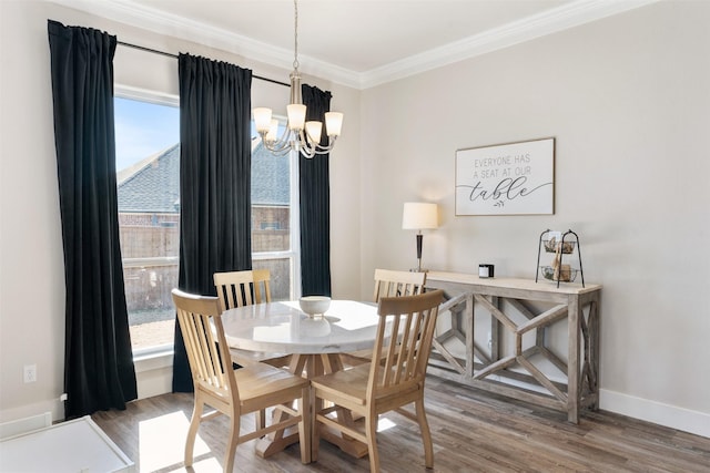 dining room with a chandelier, crown molding, baseboards, and wood finished floors