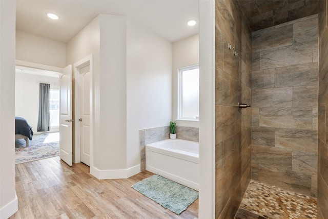 bathroom with a garden tub, connected bathroom, wood finished floors, tiled shower, and baseboards