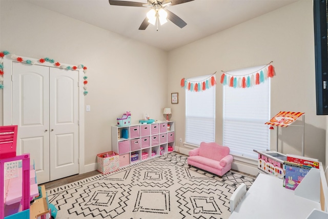 playroom with a ceiling fan and baseboards