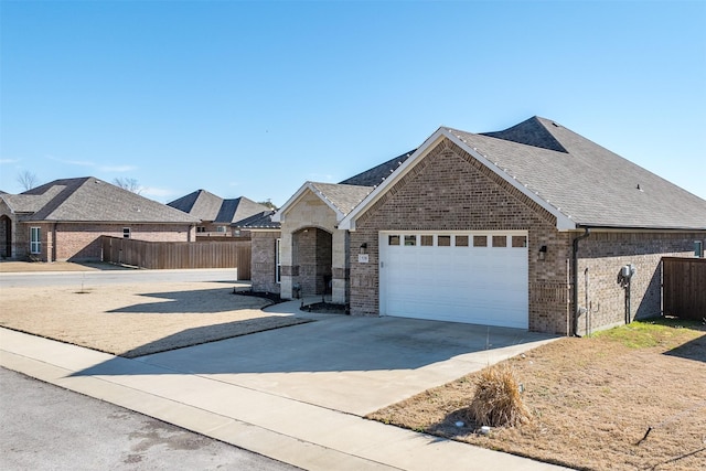 view of front of house with driveway, a shingled roof, fence, and brick siding