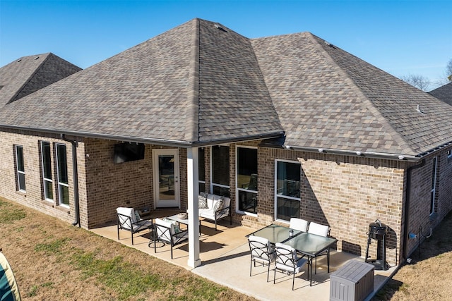 back of property featuring a shingled roof, a patio area, brick siding, and an outdoor hangout area