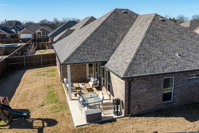 back of property with a shingled roof, a lawn, a patio, a fenced backyard, and brick siding