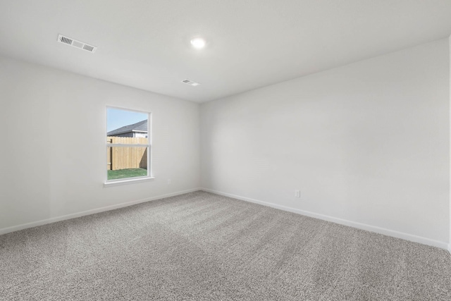 spare room featuring carpet, visible vents, and baseboards