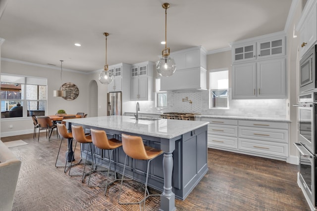 kitchen featuring arched walkways, appliances with stainless steel finishes, a sink, and ornamental molding