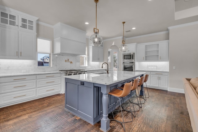 kitchen with arched walkways, appliances with stainless steel finishes, a sink, and white cabinetry