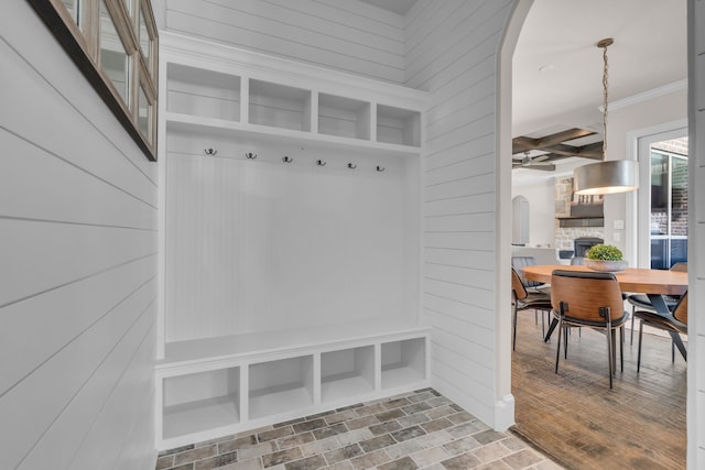 mudroom featuring ornamental molding, arched walkways, a fireplace, and wood walls