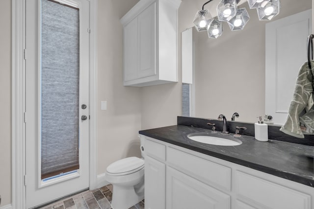 bathroom with toilet, baseboards, and vanity