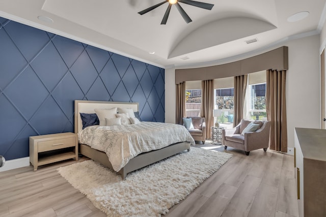 bedroom with baseboards, visible vents, an accent wall, ornamental molding, and light wood-style floors