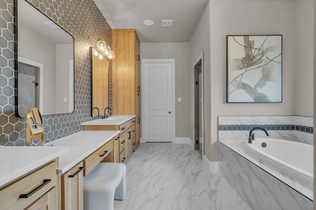 full bathroom with a garden tub, vanity, baseboards, marble finish floor, and decorative backsplash