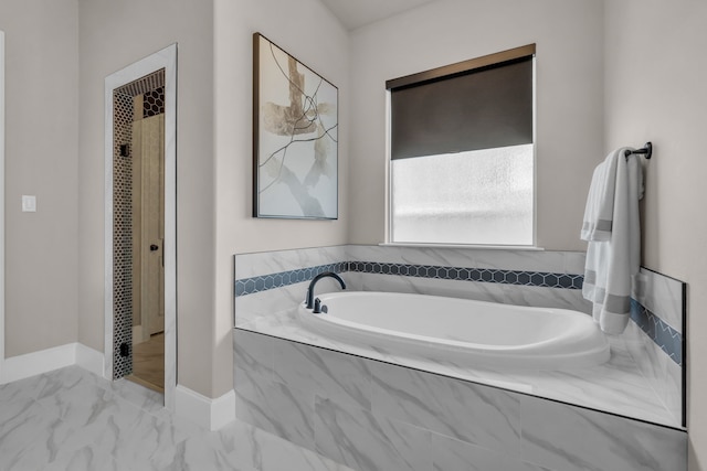 bathroom featuring marble finish floor, baseboards, and a bath