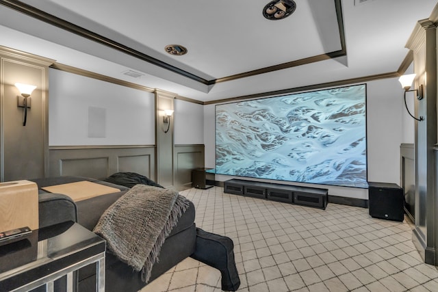 home theater room featuring a decorative wall, visible vents, wainscoting, a raised ceiling, and crown molding