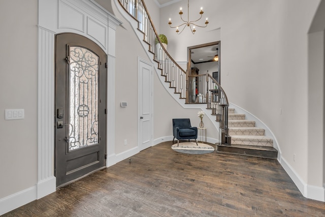 foyer entrance featuring baseboards, a high ceiling, stairway, and wood finished floors