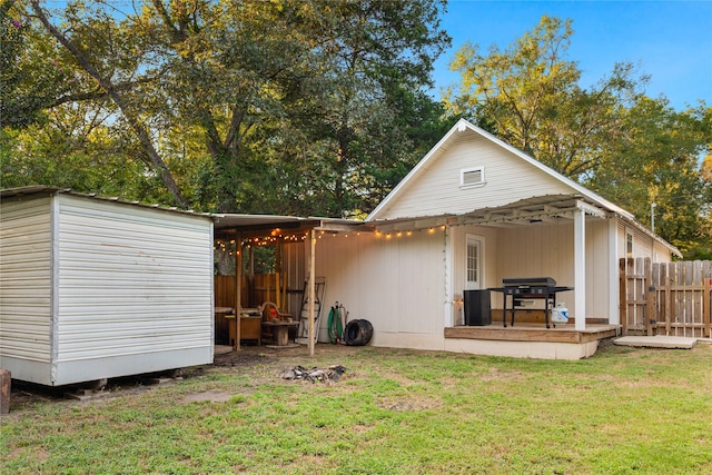 rear view of house featuring a lawn and fence