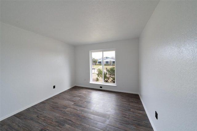 spare room with baseboards and dark wood finished floors