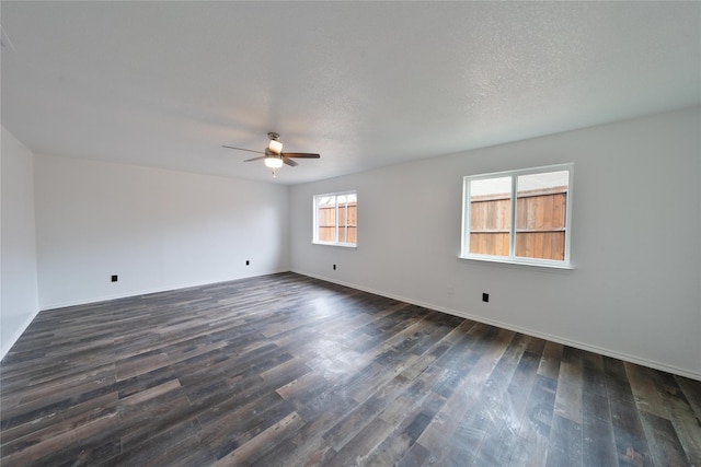 spare room featuring ceiling fan, a textured ceiling, baseboards, and dark wood-type flooring