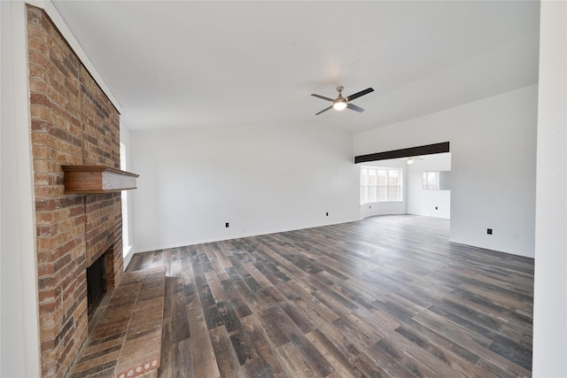 unfurnished living room with a brick fireplace, dark wood finished floors, and a ceiling fan