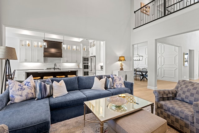 living area with light wood-style floors, a high ceiling, and baseboards