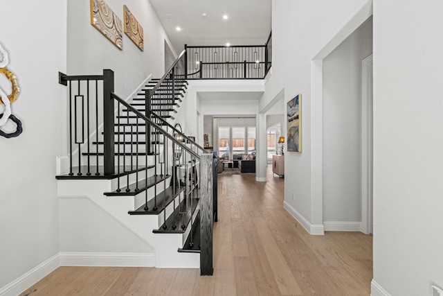 entryway with a high ceiling, wood finished floors, and baseboards