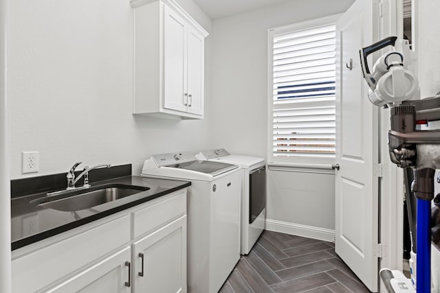 clothes washing area featuring washing machine and dryer, a sink, cabinet space, and baseboards