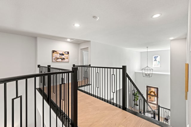 hall featuring recessed lighting, wood finished floors, an upstairs landing, and a notable chandelier