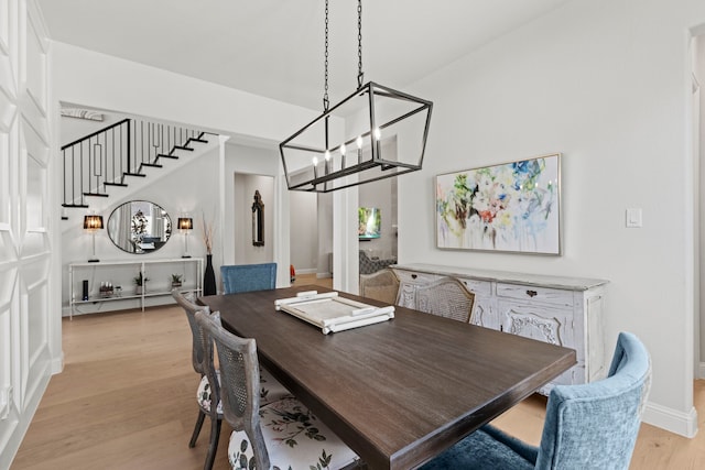 dining space with light wood-style floors, baseboards, and stairs