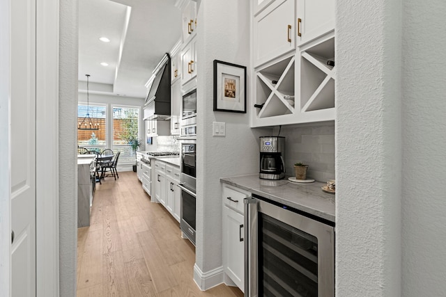 kitchen featuring light wood-type flooring, wine cooler, white cabinets, and premium range hood