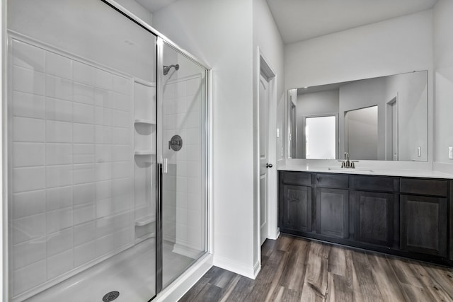 bathroom with a stall shower, vanity, and wood finished floors