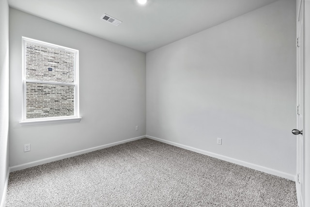 carpeted spare room with visible vents and baseboards