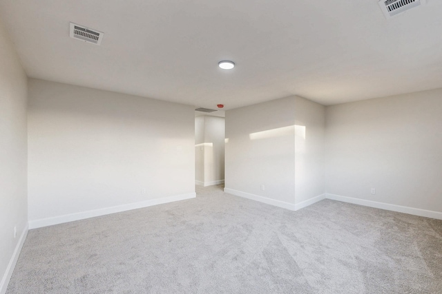 unfurnished room with baseboards, visible vents, and light colored carpet