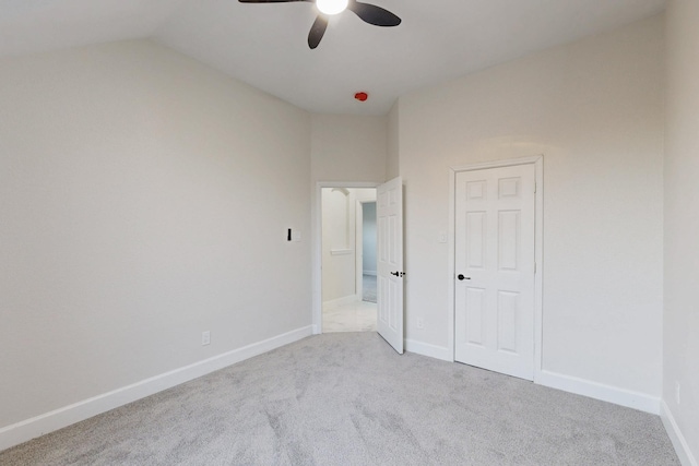 unfurnished bedroom featuring a ceiling fan, lofted ceiling, light carpet, and baseboards