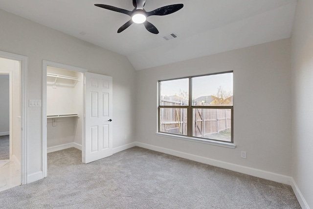 unfurnished bedroom with vaulted ceiling, a spacious closet, light carpet, and visible vents