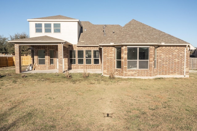 back of house featuring a yard, brick siding, a patio, and fence