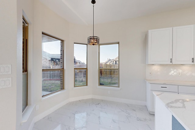 unfurnished dining area featuring baseboards, marble finish floor, and a healthy amount of sunlight