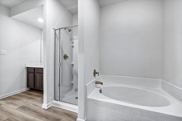 full bath with a stall shower, a garden tub, vanity, and wood finished floors