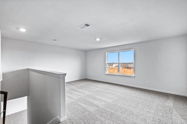 empty room with carpet floors, visible vents, and baseboards