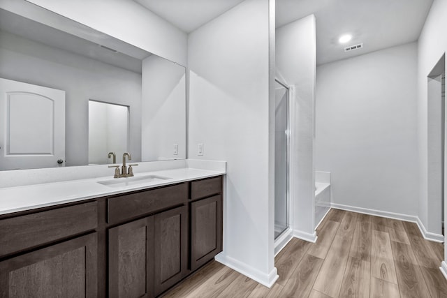 full bath with a stall shower, baseboards, wood finished floors, and vanity