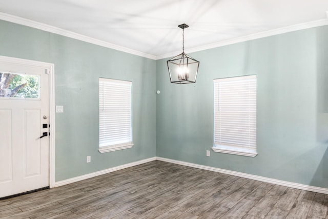 interior space with ornamental molding, baseboards, an inviting chandelier, and wood finished floors