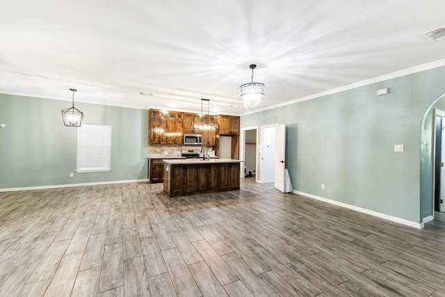 kitchen featuring arched walkways, light countertops, appliances with stainless steel finishes, and pendant lighting