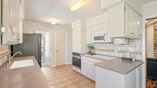 kitchen featuring stainless steel appliances, a sink, white cabinetry, backsplash, and crown molding