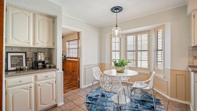 dining room featuring a wainscoted wall, light tile patterned floors, and crown molding