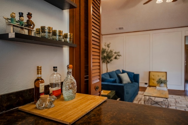 interior space featuring a wainscoted wall, a dry bar, a ceiling fan, and a decorative wall