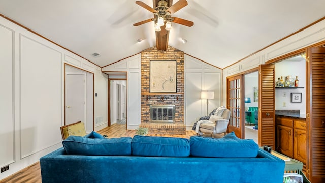 living room featuring visible vents, light wood-style flooring, vaulted ceiling with beams, french doors, and a fireplace