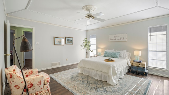 bedroom featuring dark wood-type flooring, a ceiling fan, visible vents, baseboards, and crown molding