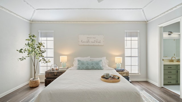 bedroom with multiple windows, baseboards, and wood finished floors